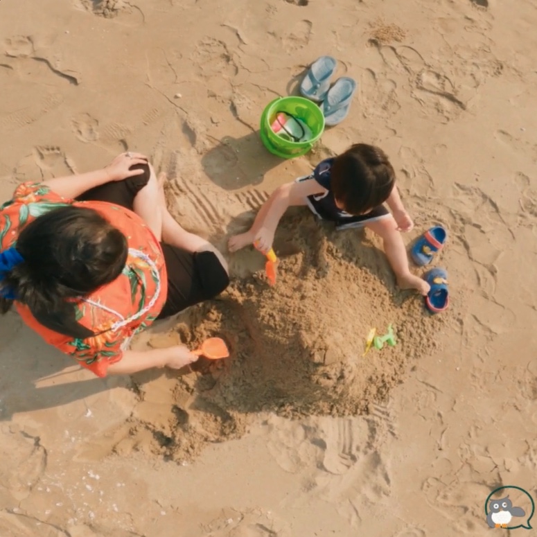And woman and a child playing with spades in the sand